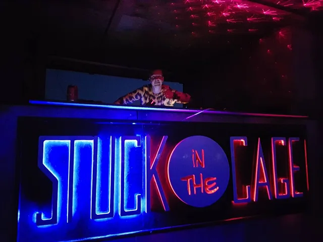 Het STUCK in the Cage-logo in blauw en rood licht