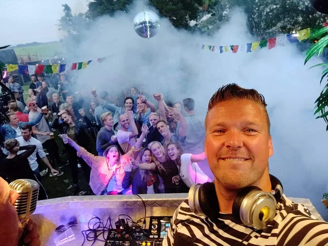 Sjon met hoofdtelefoon en het publiek op een buitenfeest