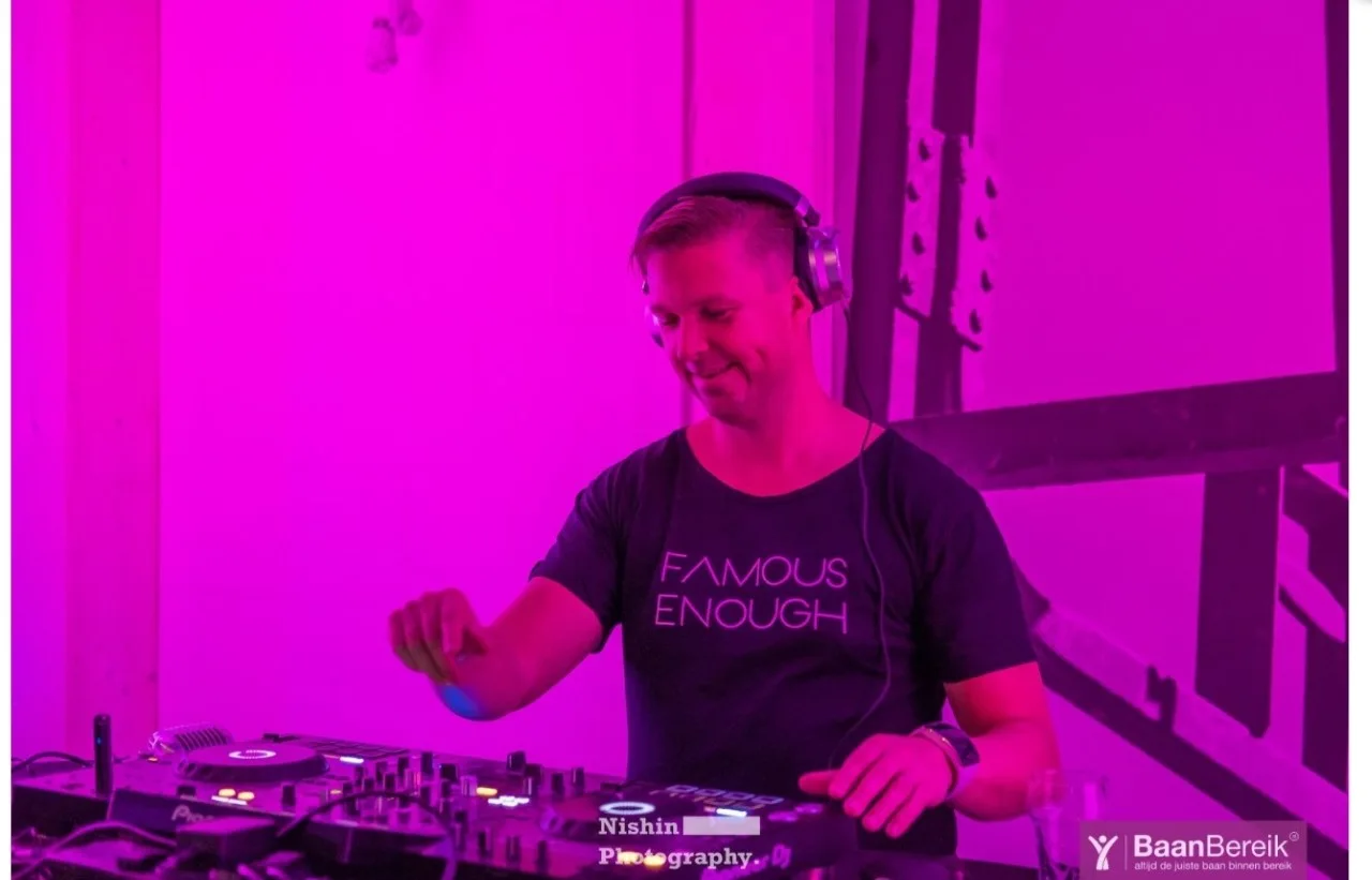 Sjon Kooy geconcentreerd achter de Pioneer DJ-spelers in roze licht