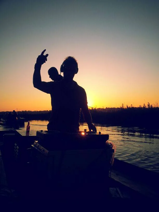 DJ-silhouet aan het water bij zonsondergang